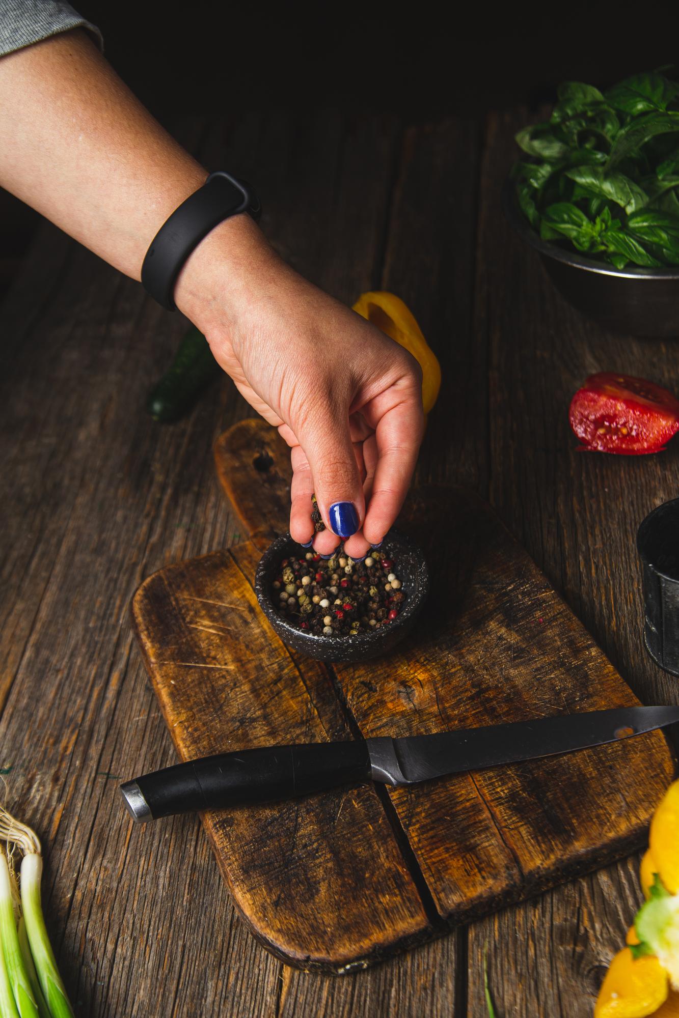 Close-up of hands seasoning a roasted vegetable dish
