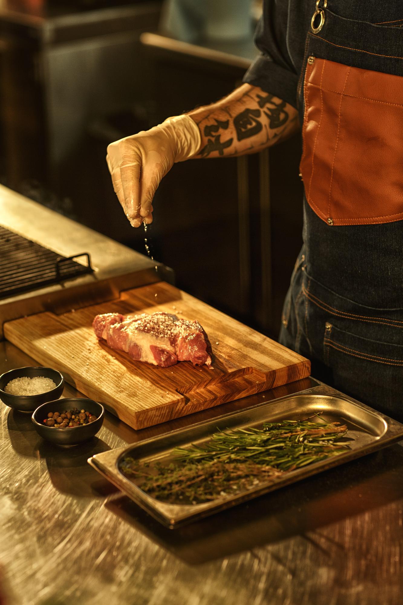 Chef carving roasted protein on butcher block