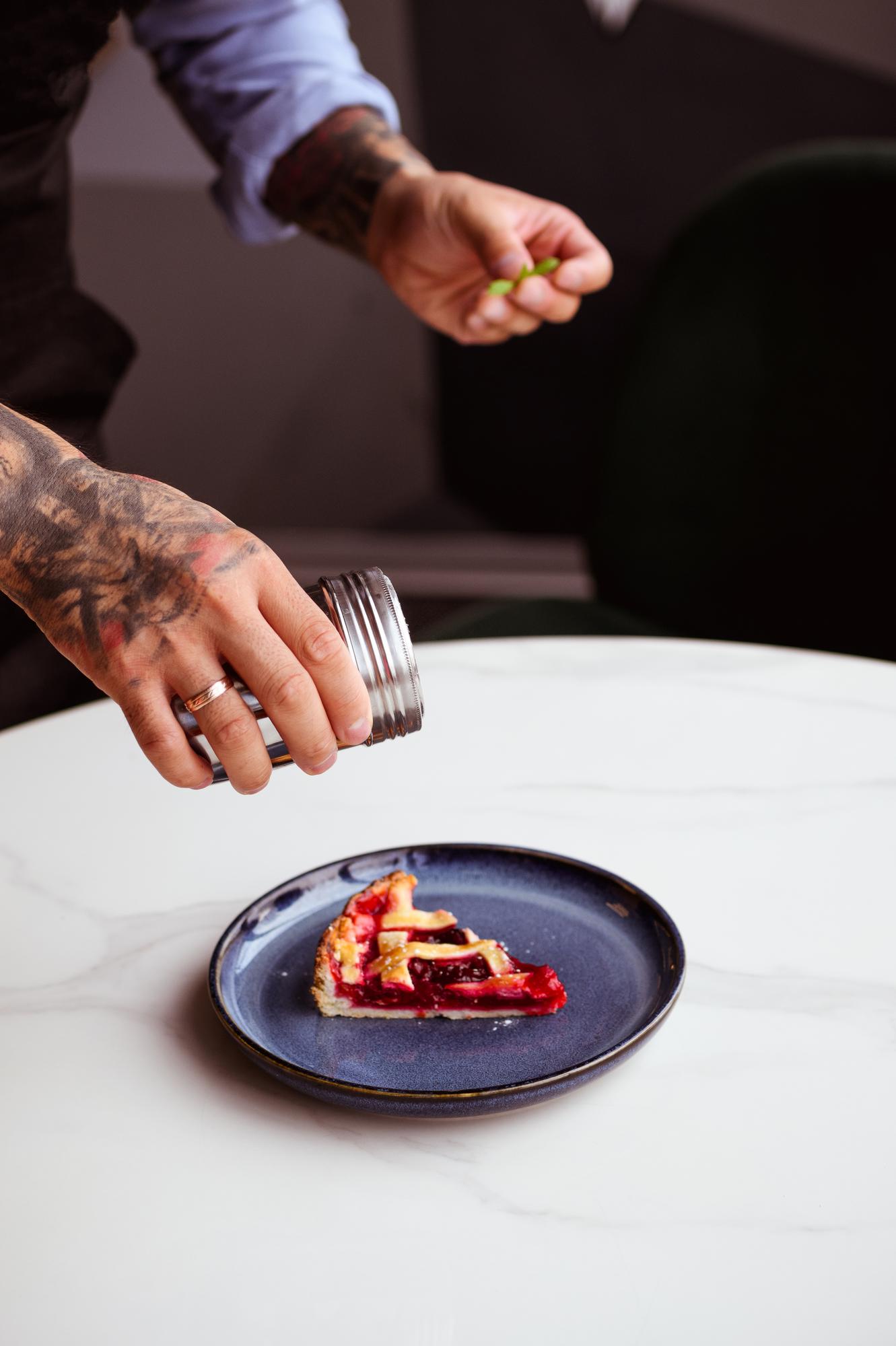 Chef plating a composed dish on dark table